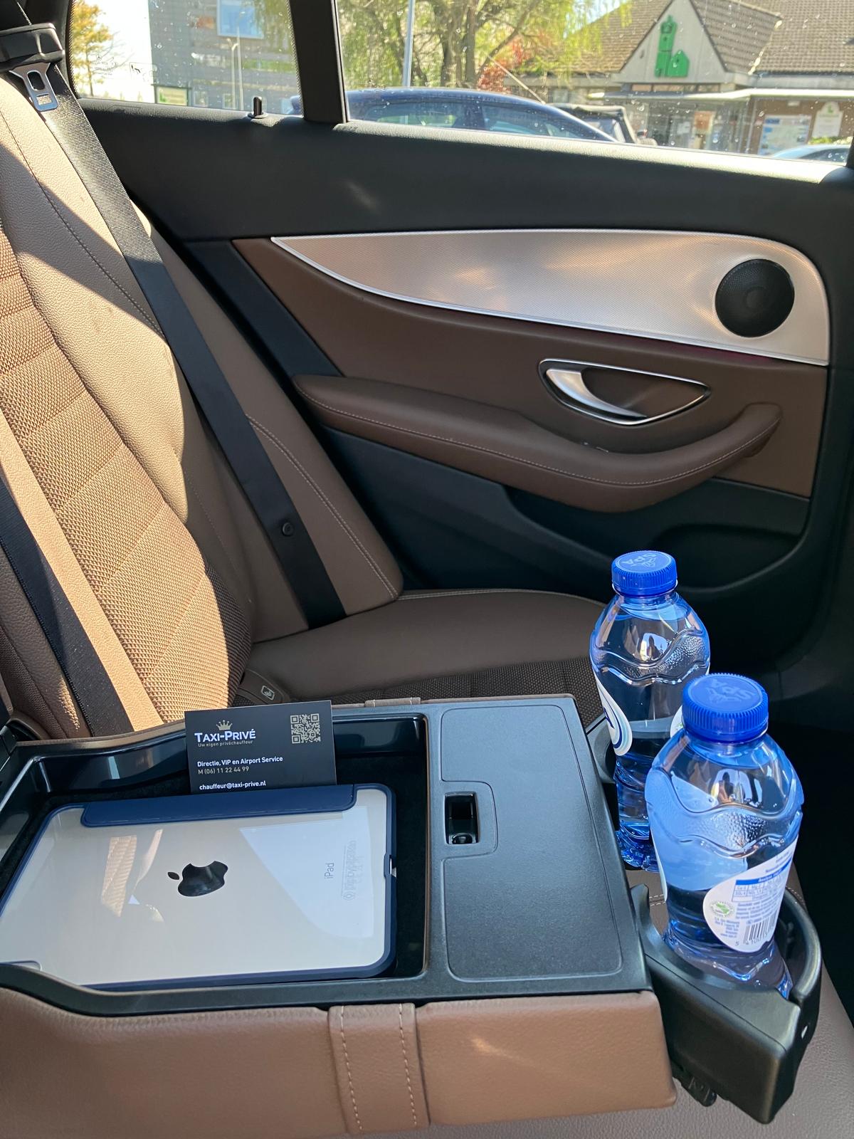 Interieur van de Taxi-Privé Mercedes met leder, iPad en flesjes water voor de gast