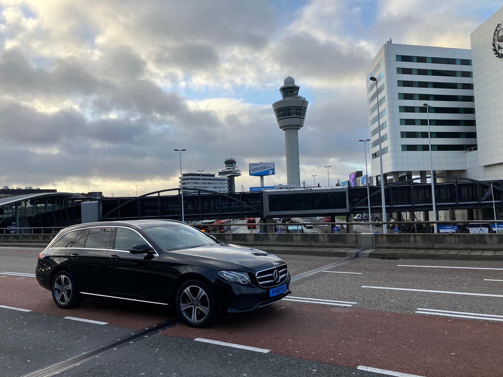 Taxi-Privé Mercedes bij Schiphol met de verkeerstoren op de achtergrond